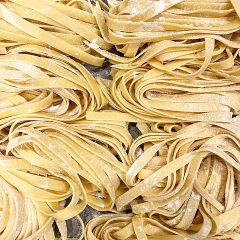 Frische Tagliatelle, zu Nestern gedreht und mit Mehl bestäubt