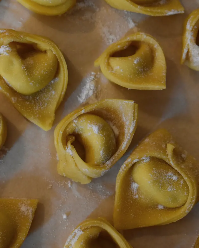 Frisch gefaltete Cappellacci, mit Mehl bestäubt, auf Backpapier